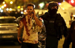 A French policeman assists a blood-covered victim near the Bataclan concert hall following attacks in Paris, France, November 14, 2015 (Photo Credit: REUTERS/Philippe Wojazer)