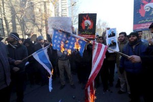 Iranian protesters holding pictures of Shi'ite cleric Sheikh Nimr al-Nimr burn a U.S. flag (R) and an Israeli flag during a demonstration at the KSA Embassy in Tehran (Photo Credit: Reuters)