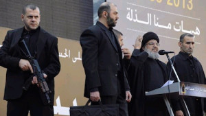 Nasrallah on stage with armed guard and suitcase with ballistic protection against assassination attempts, which is bulletproof and bombproof (Photo Credit- Ynet)